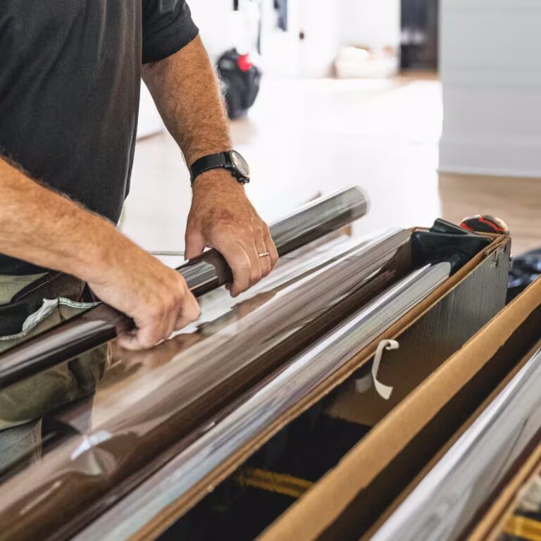 Person handling rolled material in a cardboard box on a table