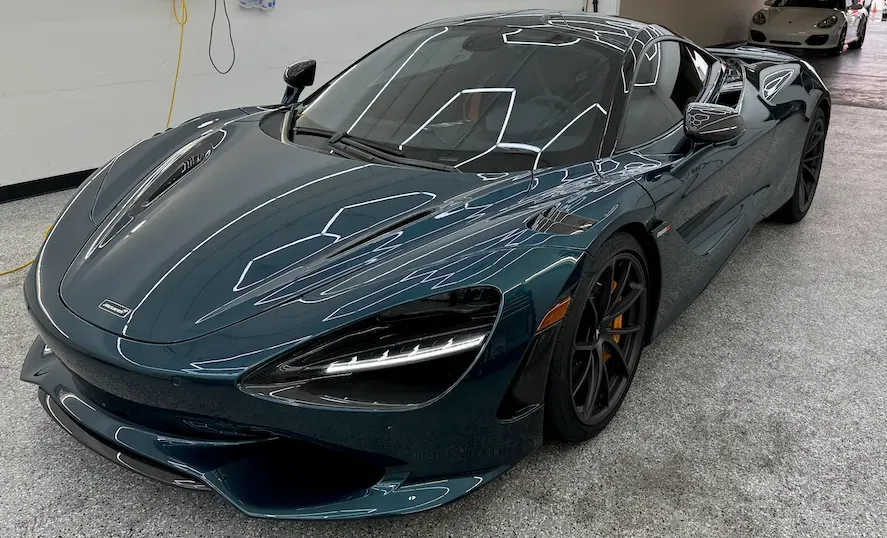 Dark blue sports car in a showroom, front three-quarter view with sleek aerodynamic design