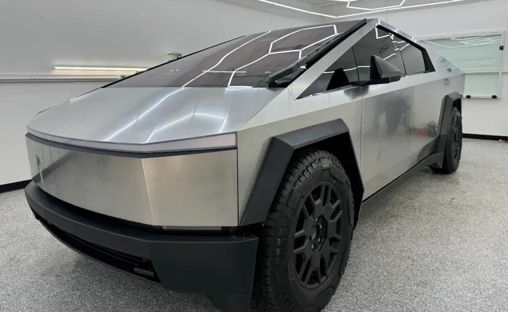 Silver Tesla Cybertruck parked indoors on a showroom floor, front-left view