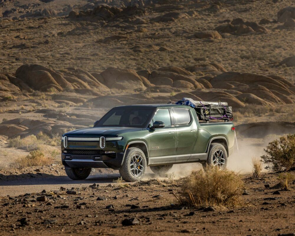 Green pickup truck driving through a dusty desert landscape