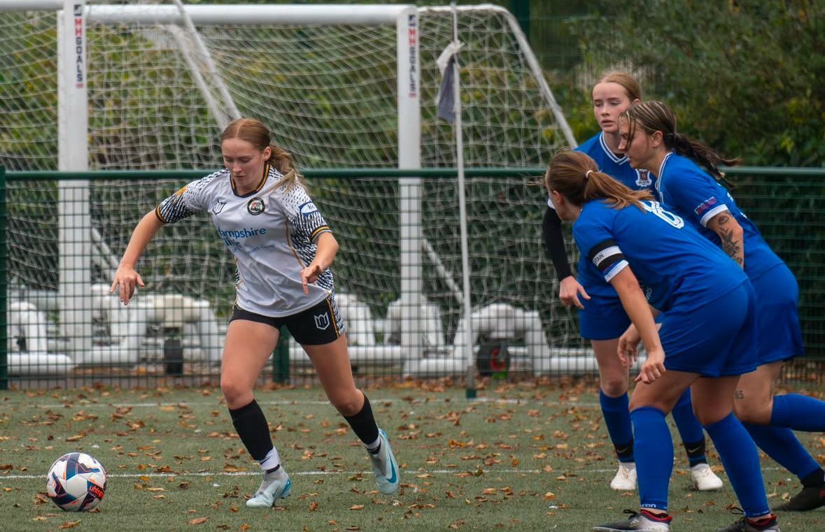 A group of young women are playing soccer on a field.
