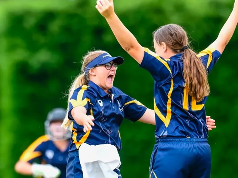 Two female softball players are celebrating on the field.