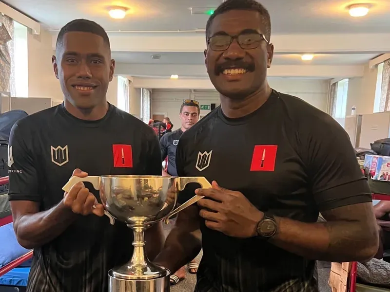 Two men are standing next to each other holding a trophy.
