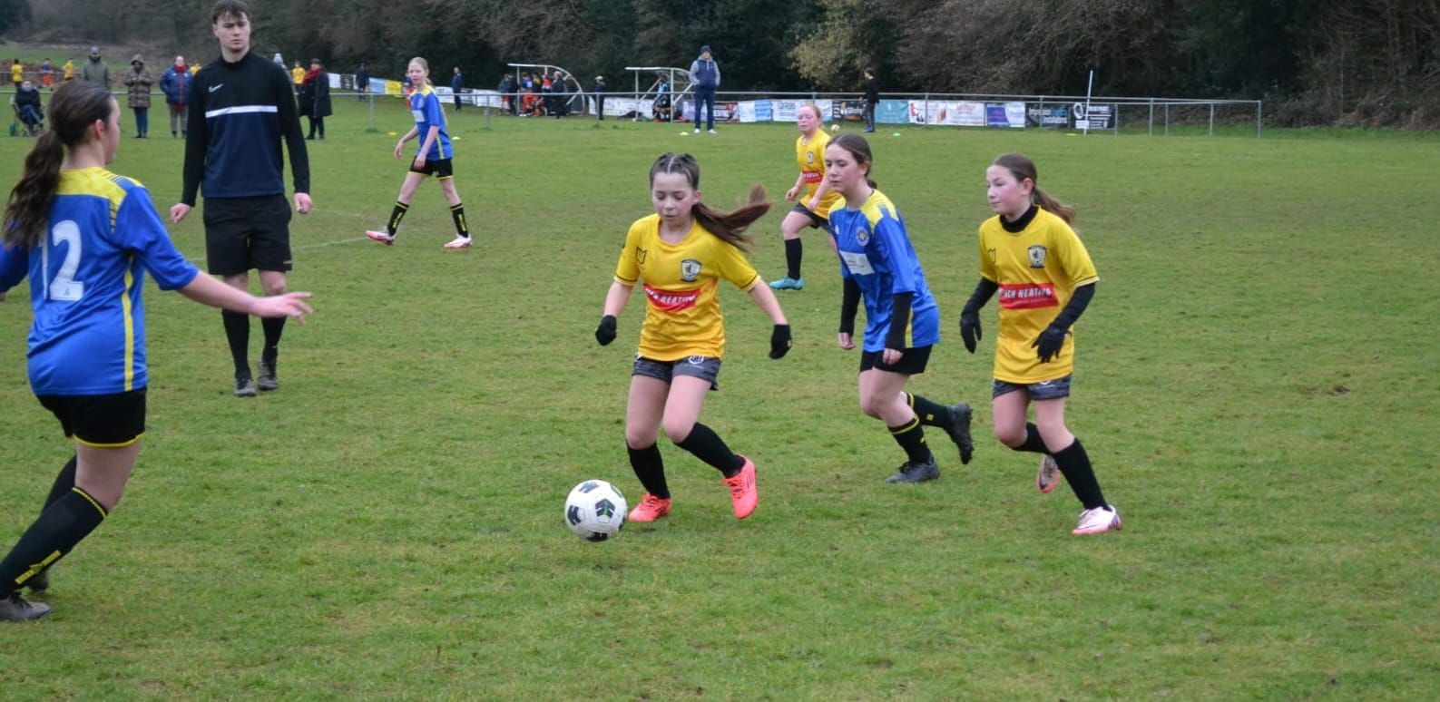 A group of young girls are playing soccer on a field.