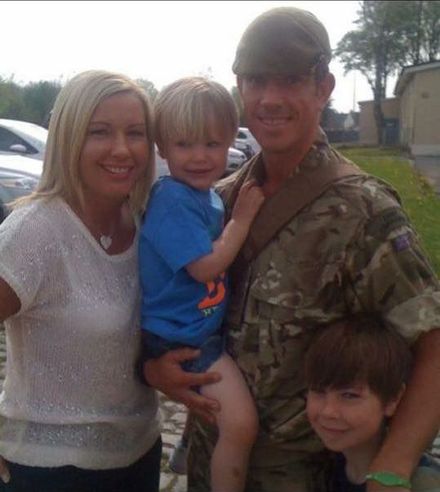 A man in a military uniform holds a little boy in his arms
