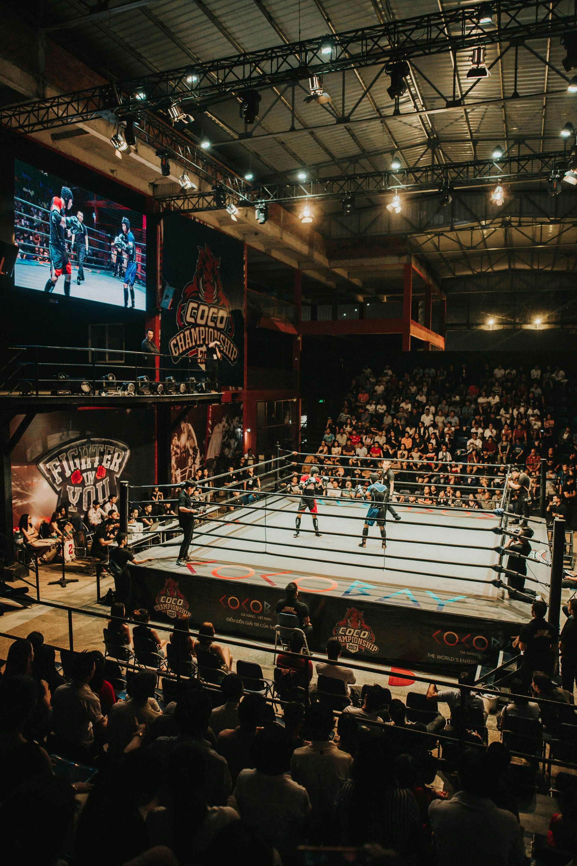 A crowd of people are watching a boxing match in a boxing ring.