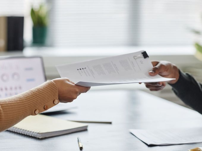 A person is handing a piece of paper to another person.