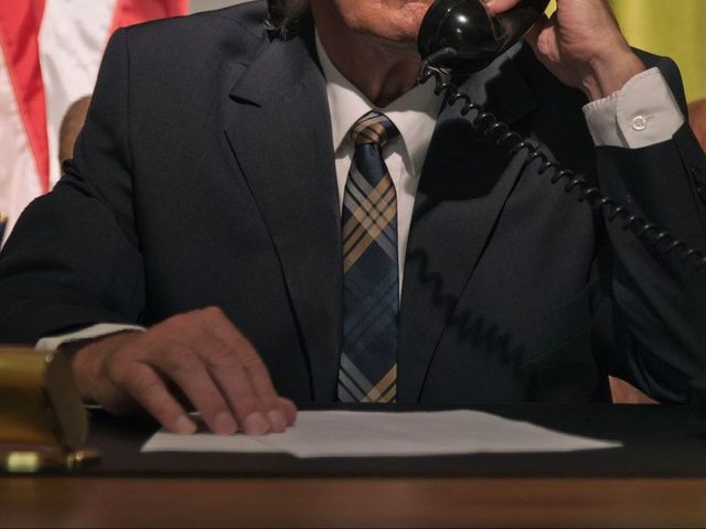 A man in a suit and tie is talking on a phone