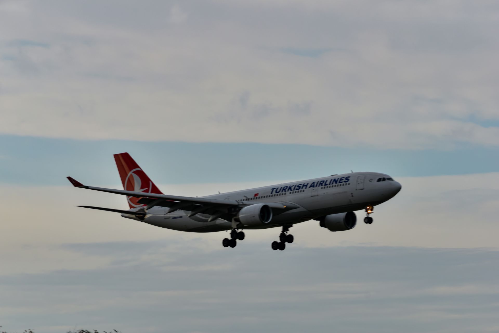 A large passenger jet is flying through a cloudy sky.