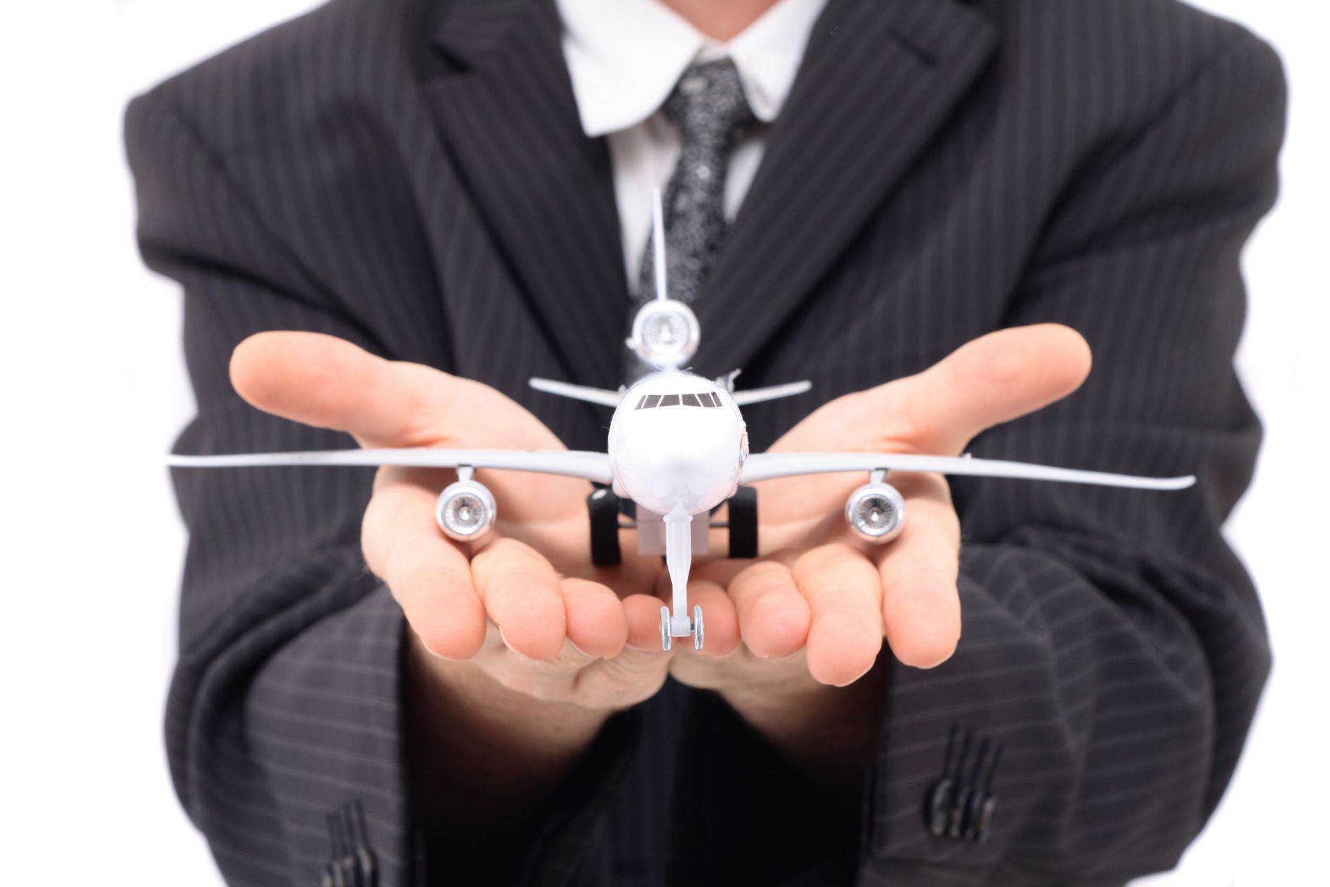A man in a suit is holding a model airplane in his hands