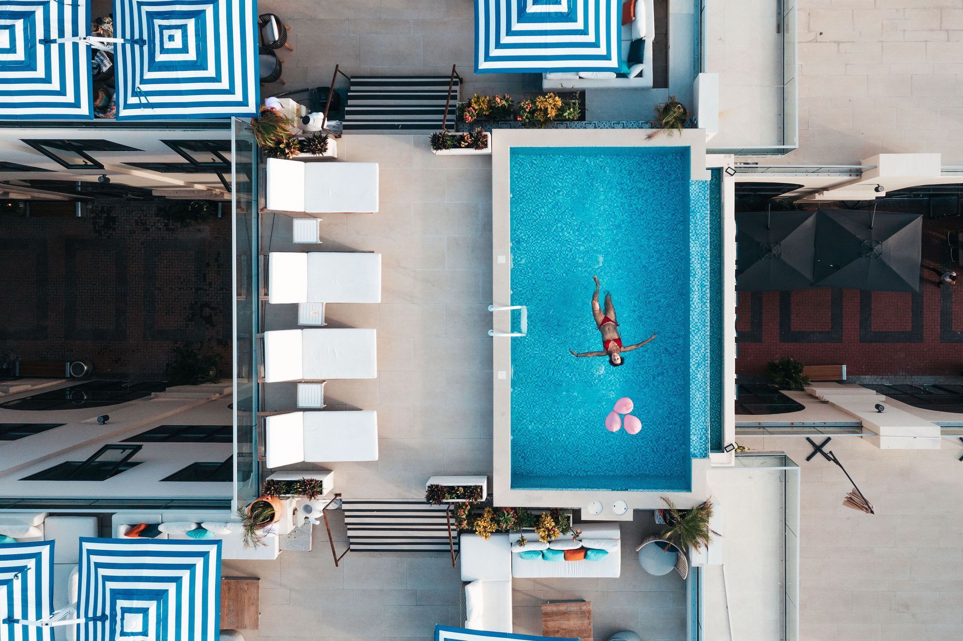 An aerial view of a swimming pool surrounded by umbrellas and chairs.