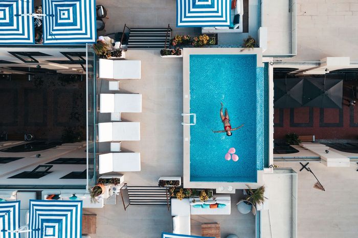 An aerial view of a swimming pool surrounded by umbrellas and chairs.