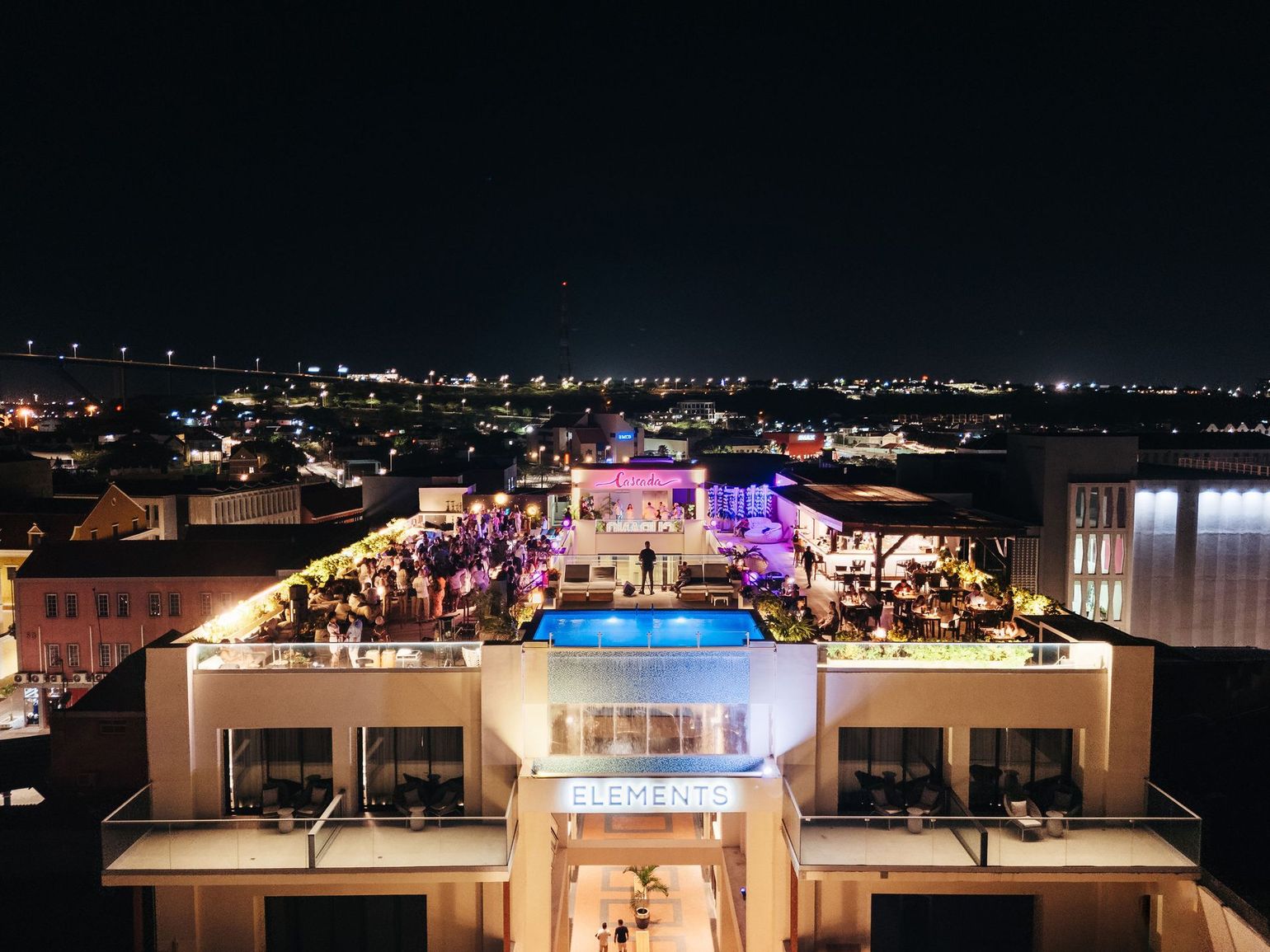 An aerial view of a large building at night with a swimming pool in the middle.