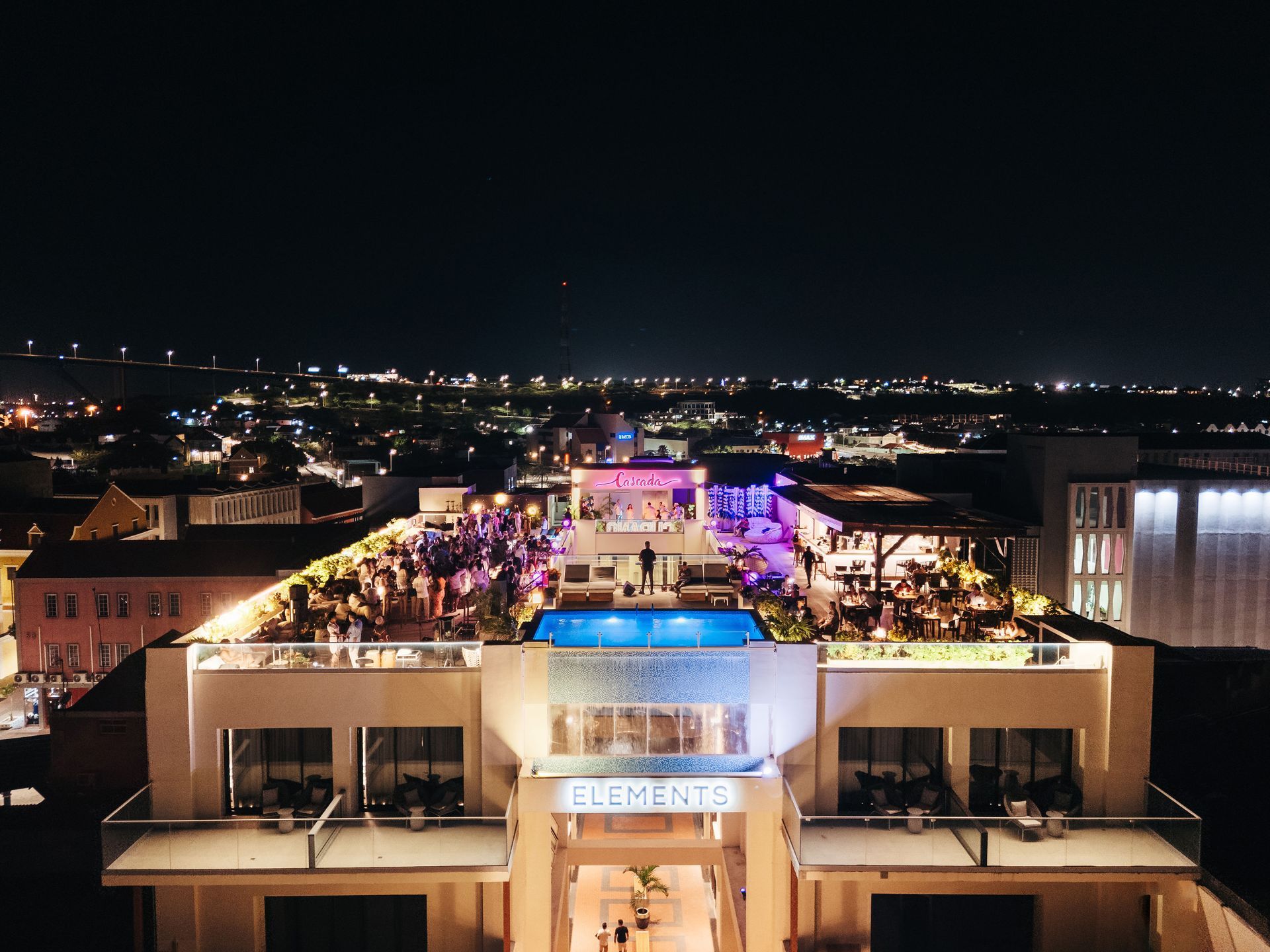 An aerial view of a large building at night with a swimming pool in the middle.