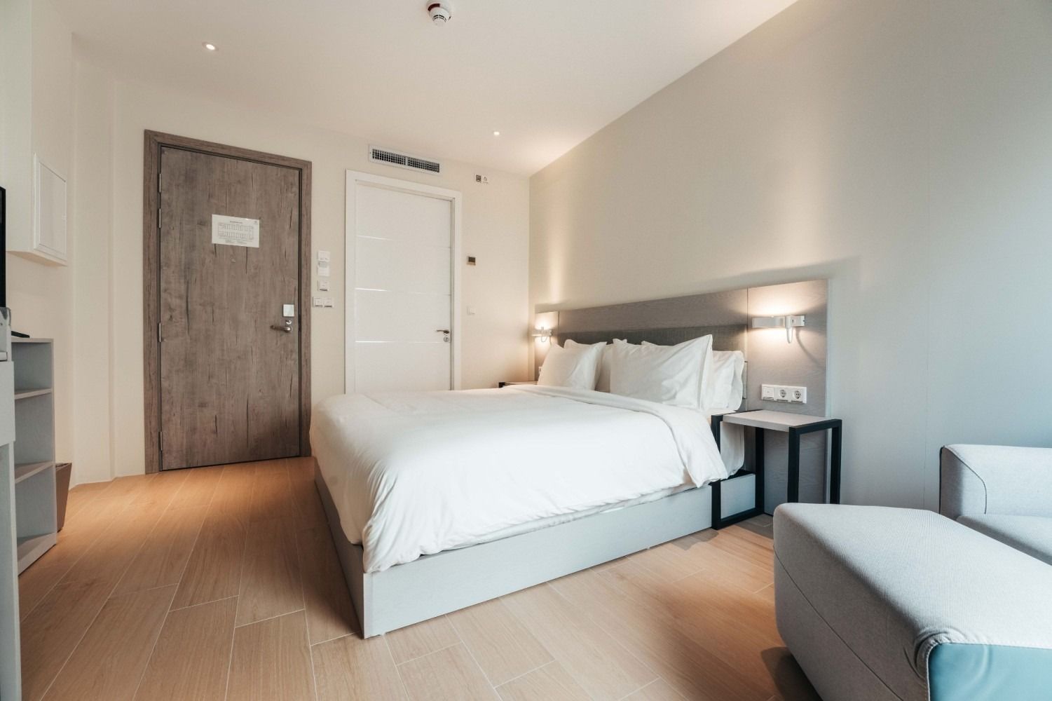 A hotel room with a king size bed and a chair.
