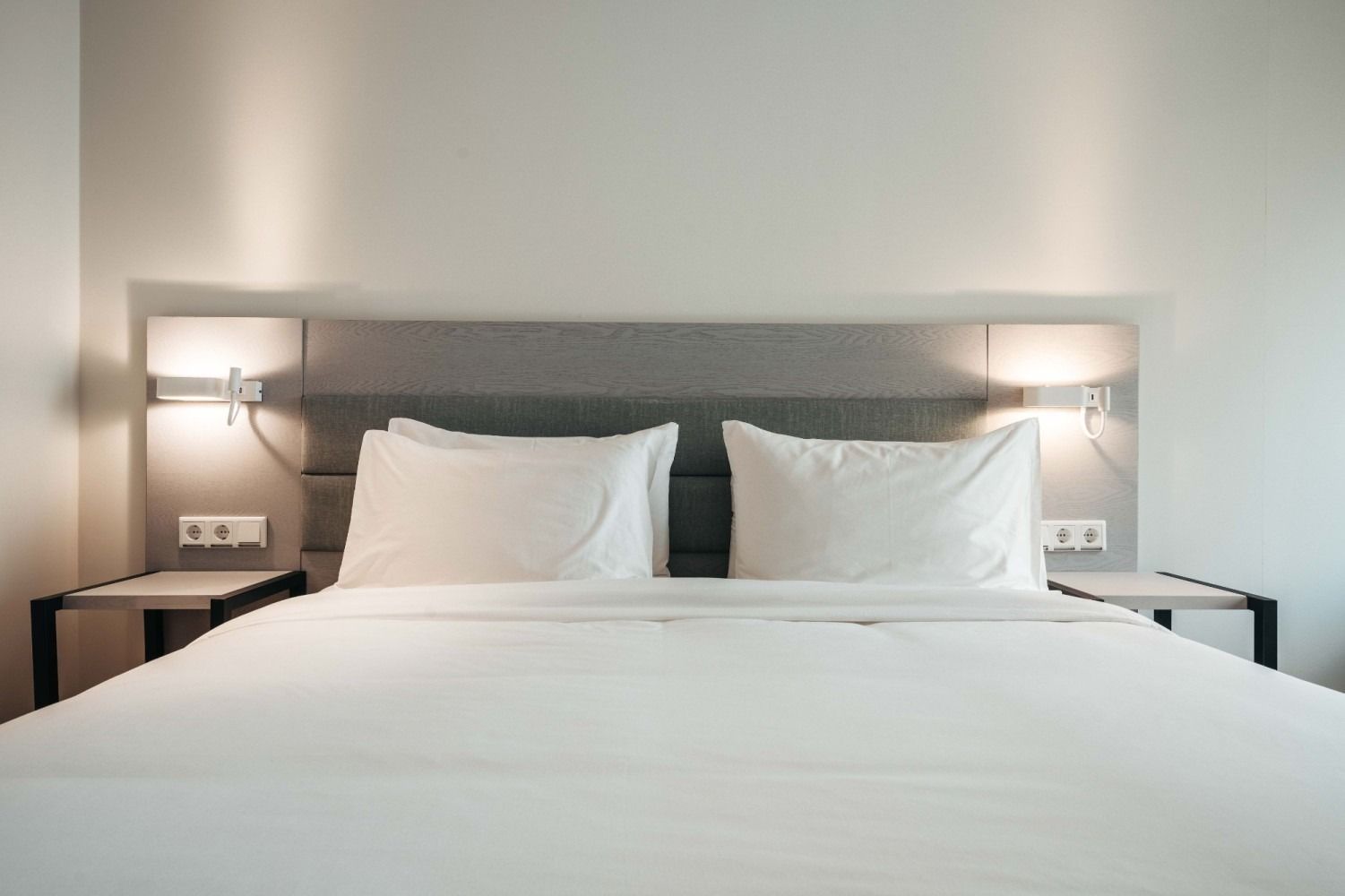 A bed with white sheets and pillows in a hotel room.