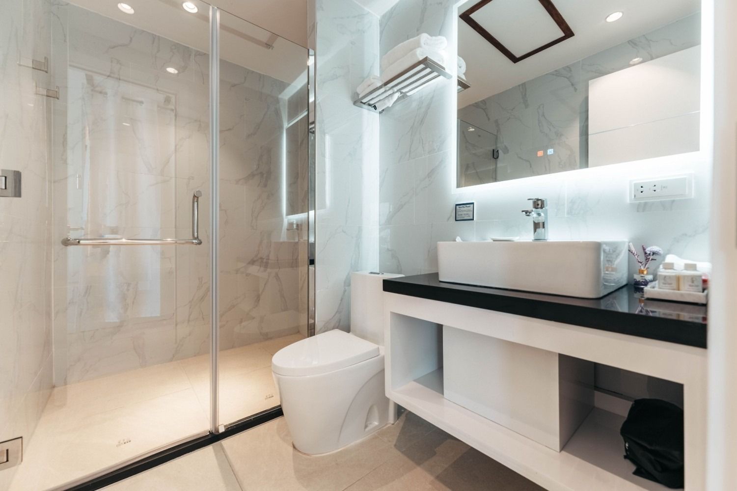 A bathroom with a toilet , sink , mirror and walk in shower.