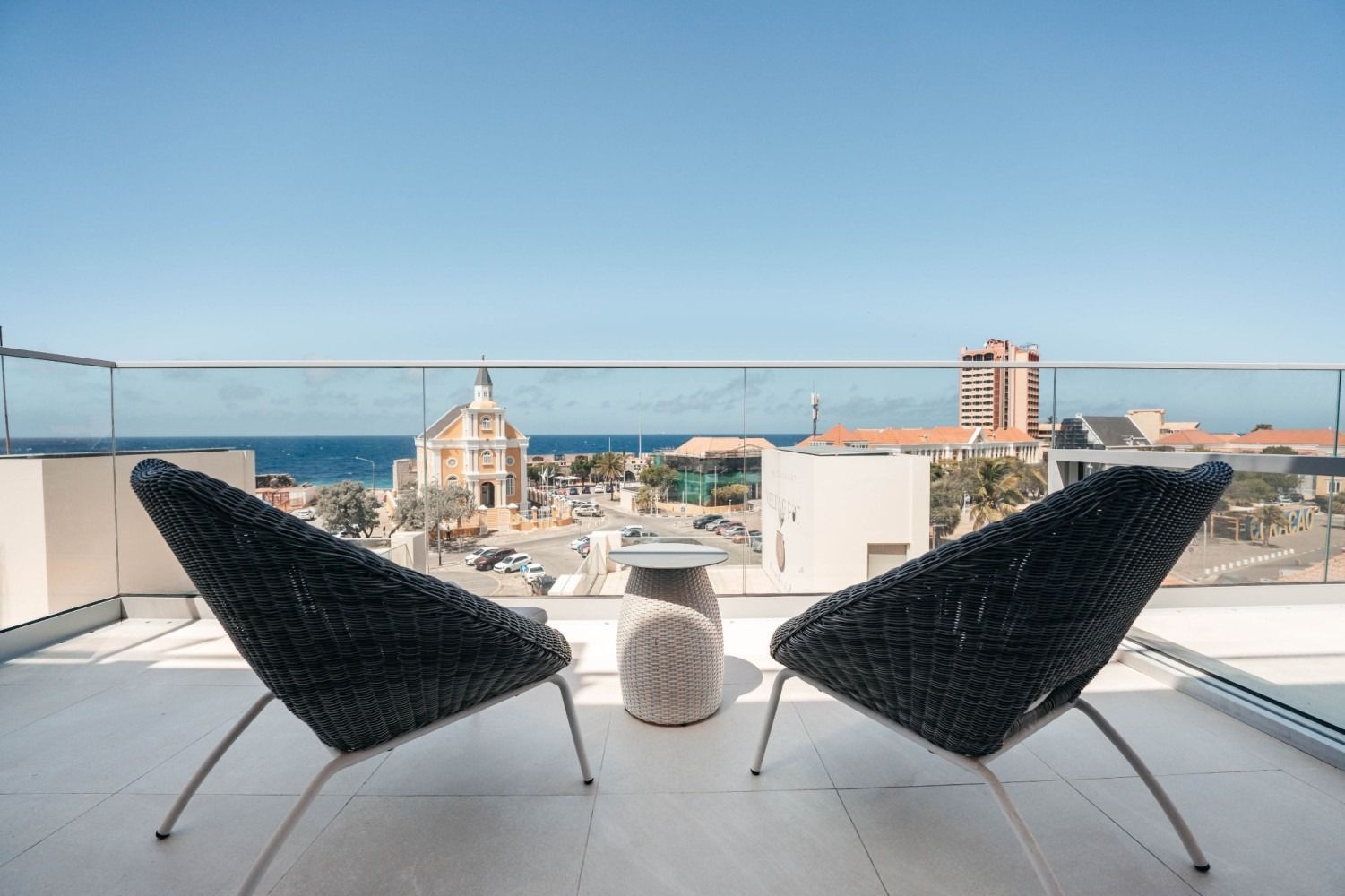 Two chairs are sitting on a balcony overlooking the ocean.