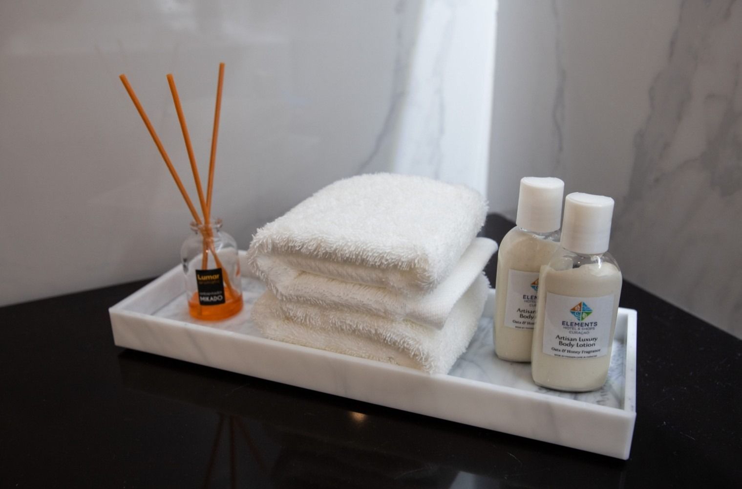A marble tray with towels and lotion on it