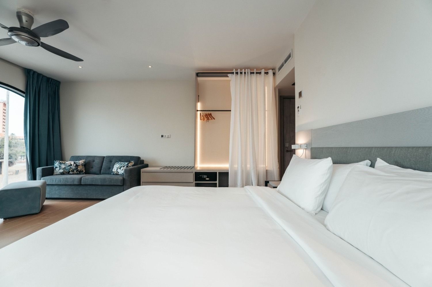 A hotel room with a bed , couch , and ceiling fan.