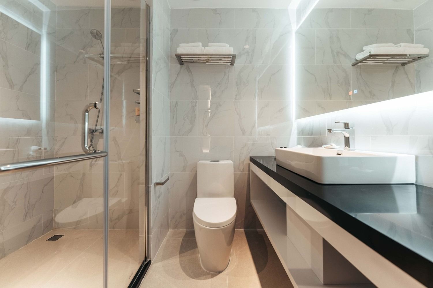 A bathroom with a toilet , sink , shower and mirror.