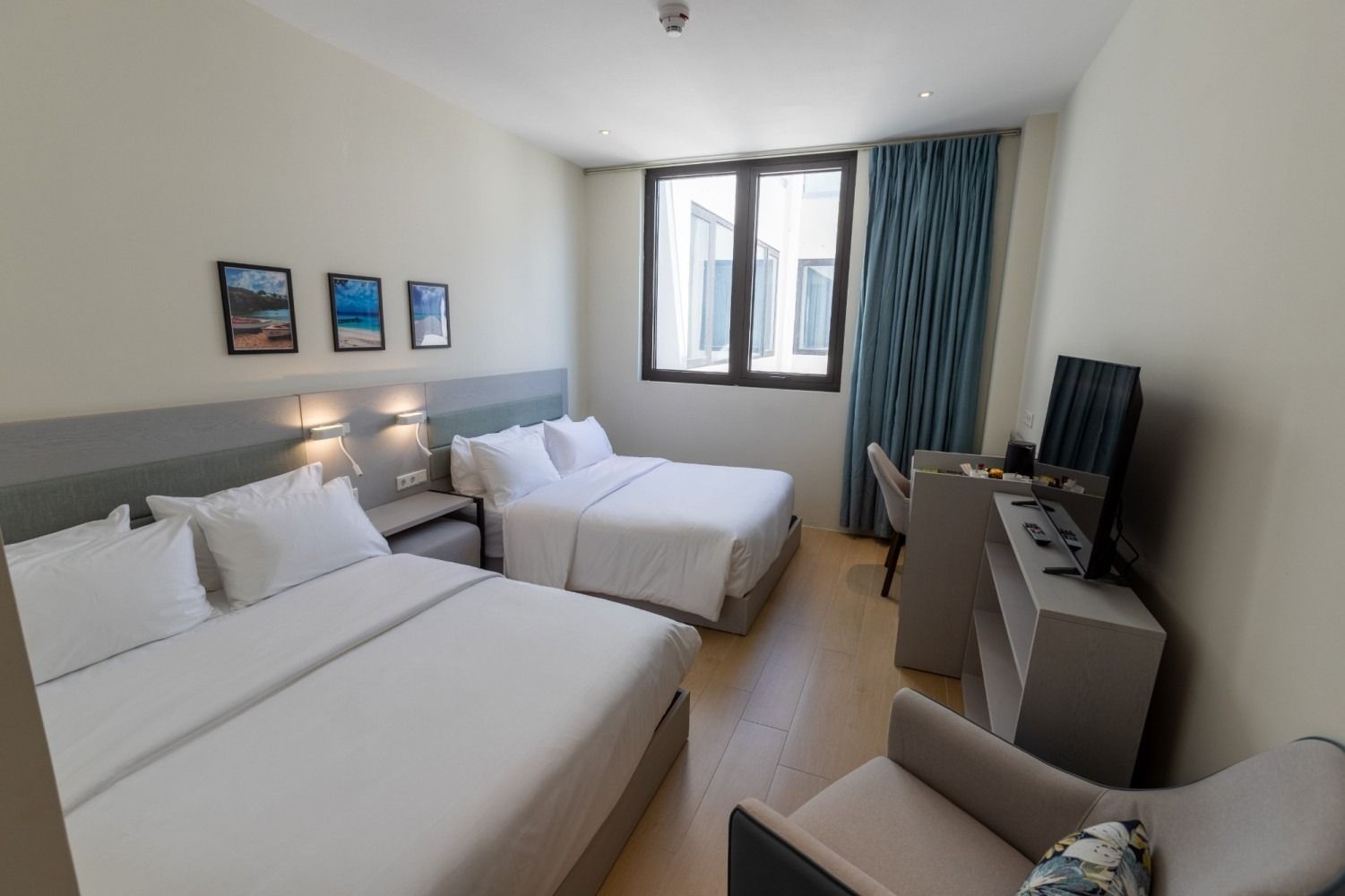 A hotel room with two beds , a chair , a desk and a television.