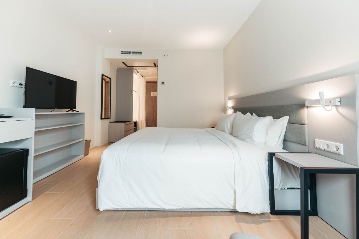 A hotel room with a king size bed and a flat screen tv.