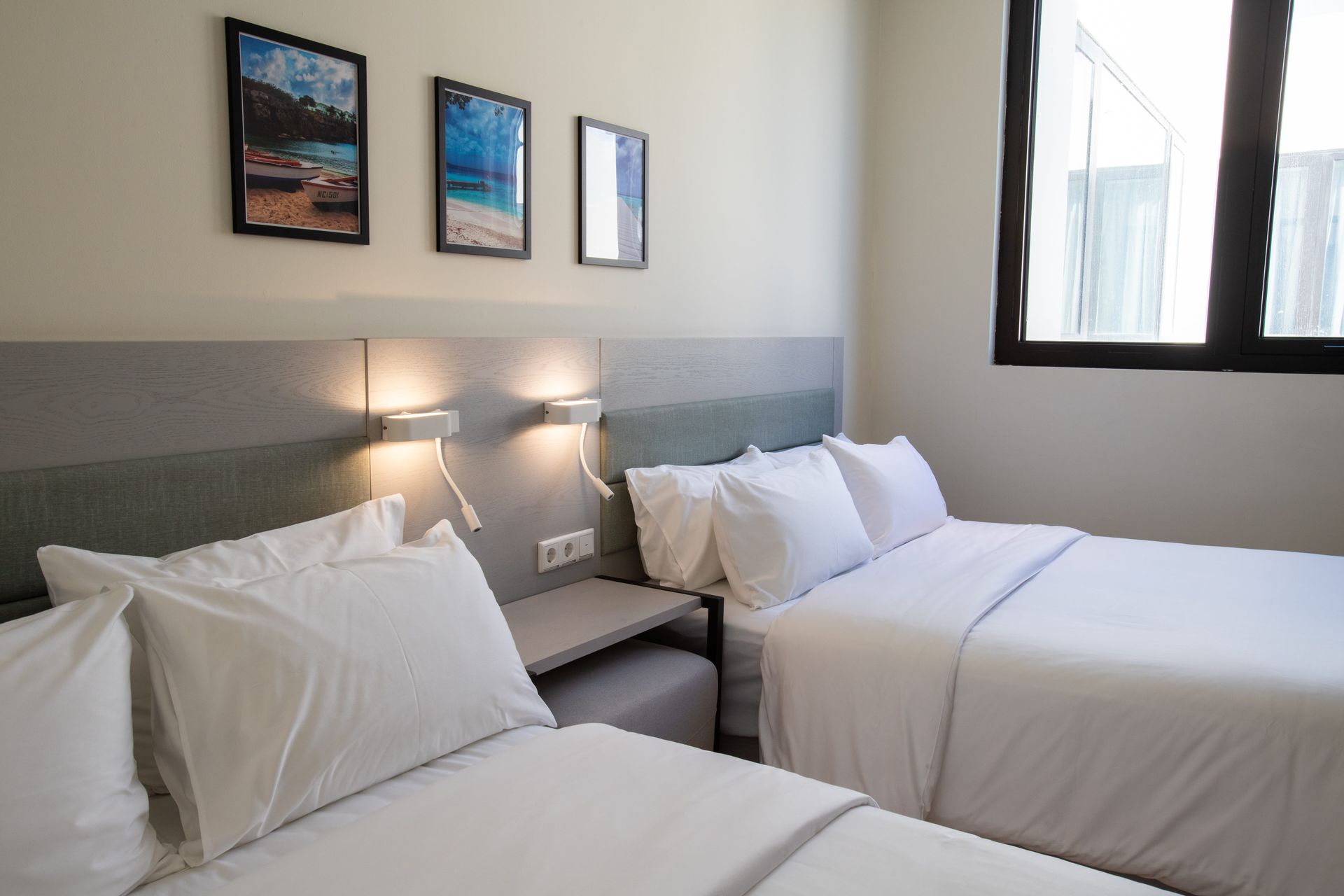 A hotel room with two beds and three pictures on the wall.
