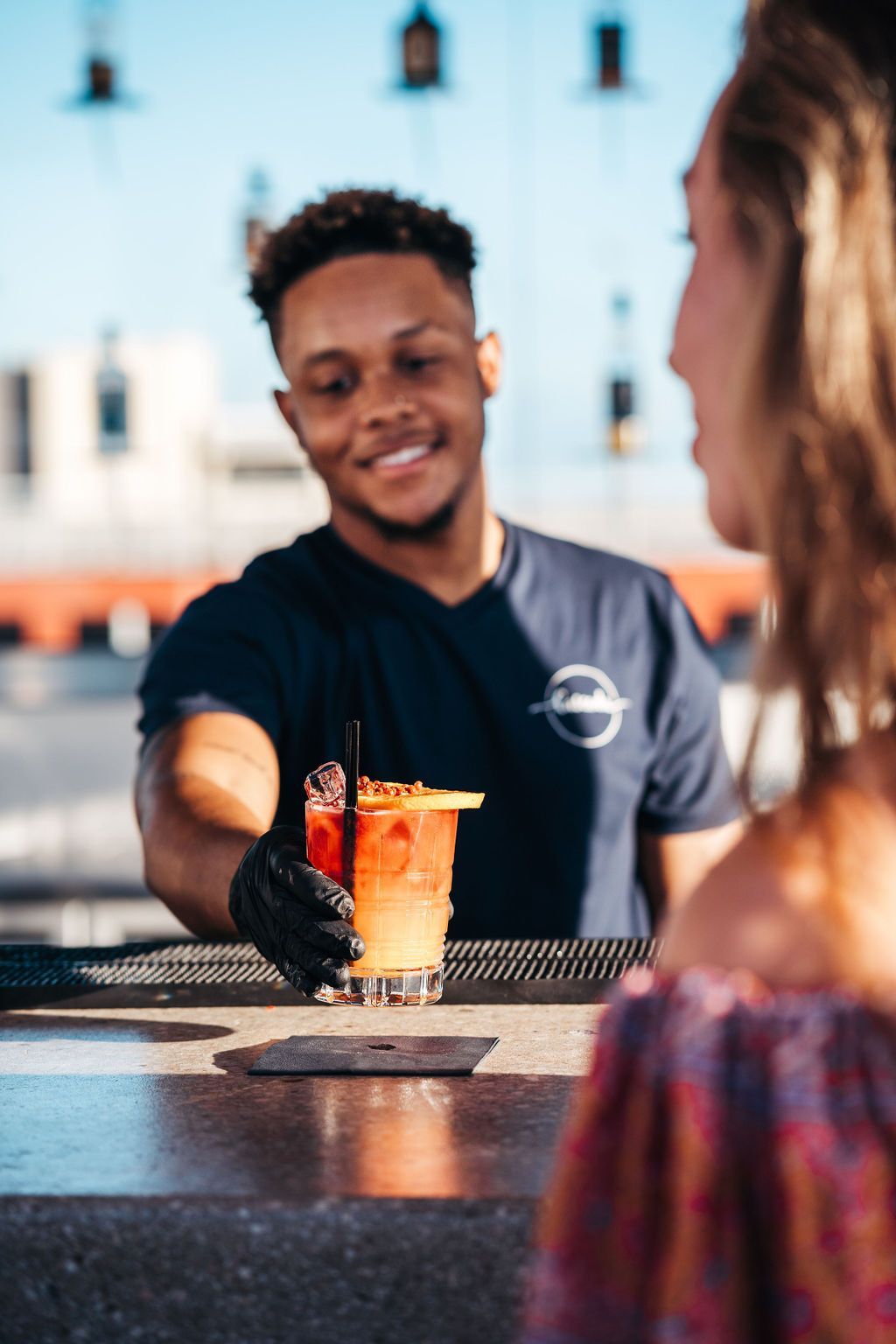 A man is serving a drink to a woman at a bar.