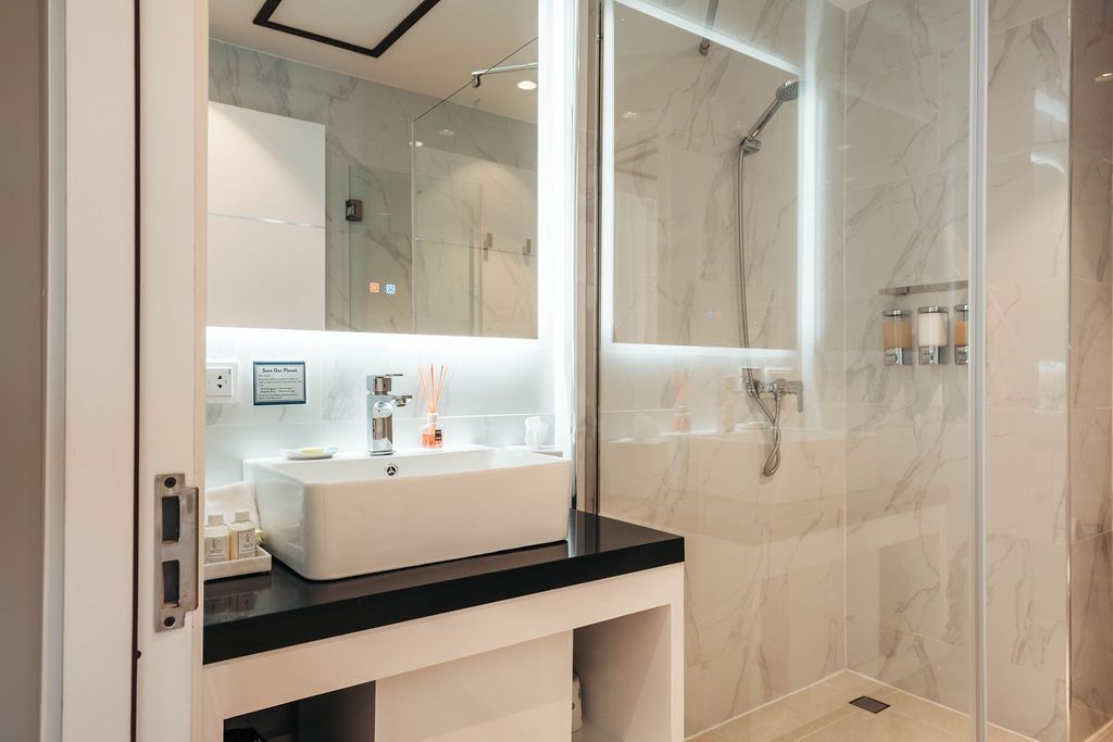 A bathroom with a sink , mirror and walk in shower.