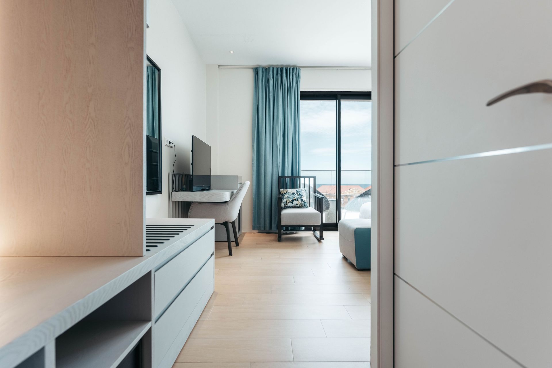 A hotel room with a bed , chair , desk and television.