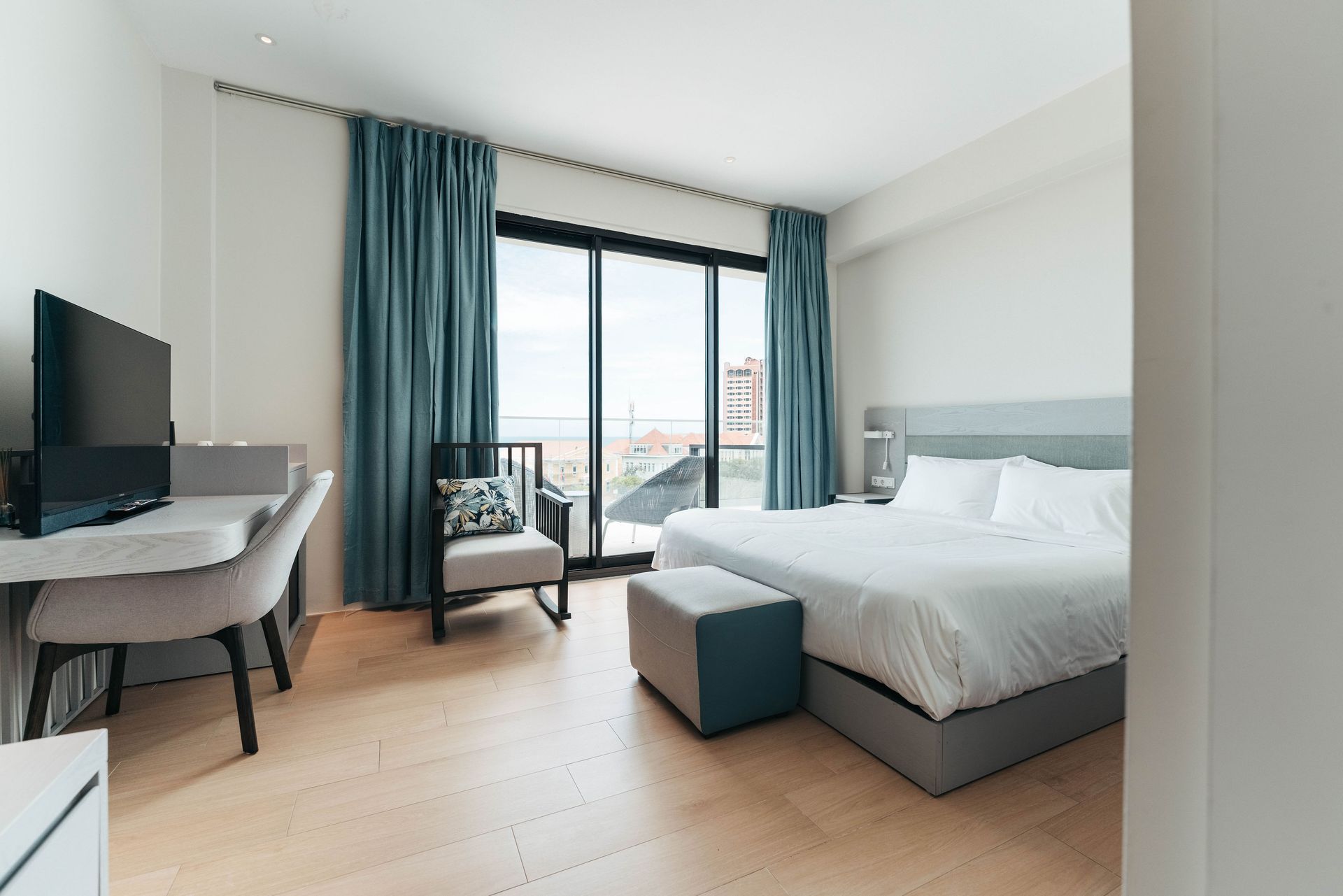 A hotel room with a bed , chair , desk and television.
