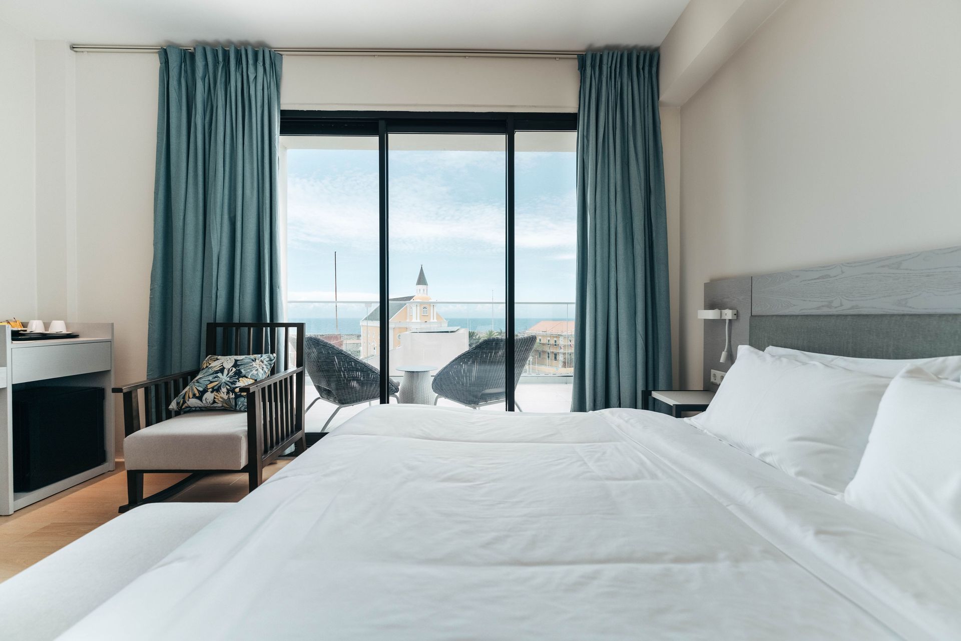 A hotel room with a bed , chair and sliding glass doors.