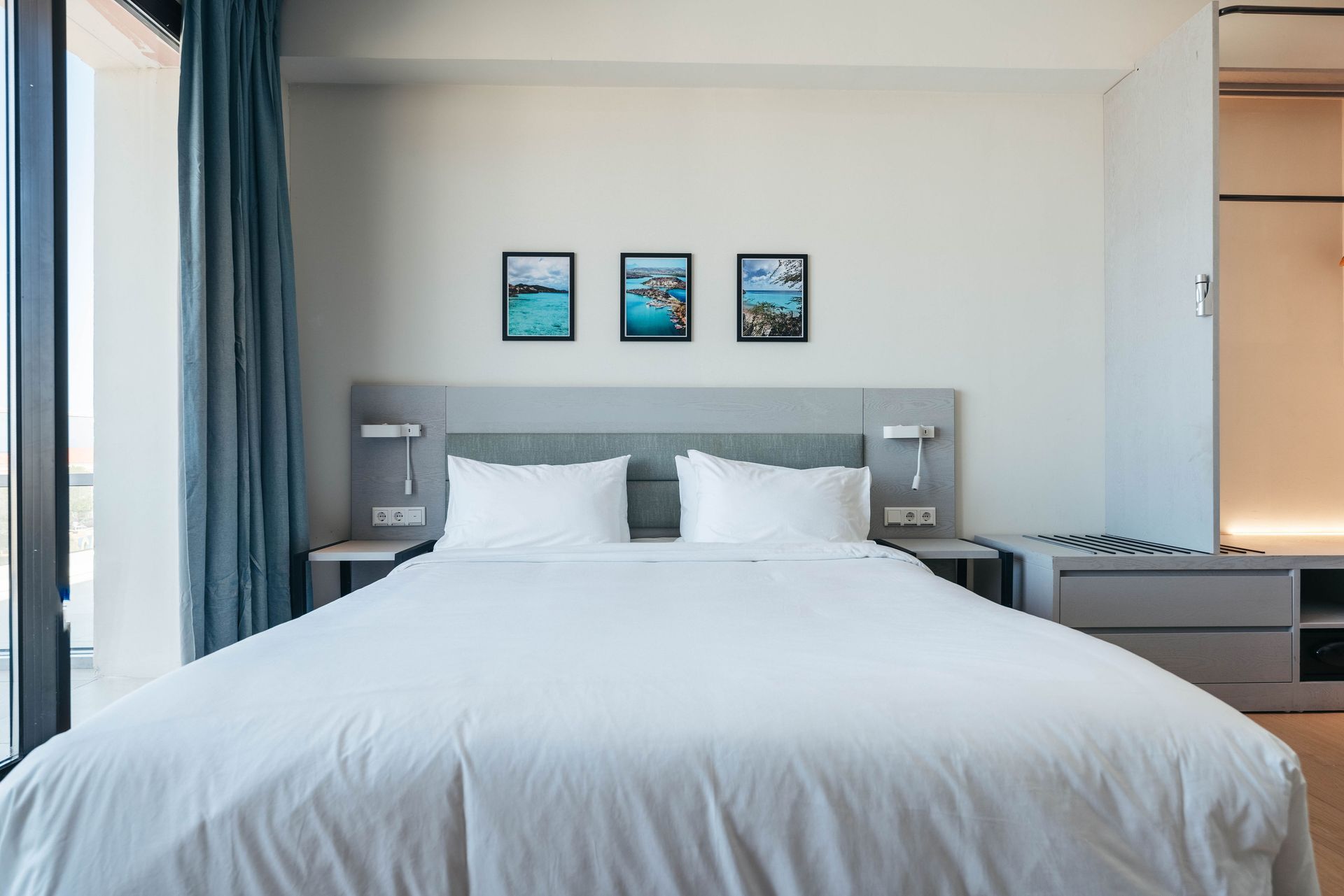 A hotel room with a large bed and three pictures on the wall.