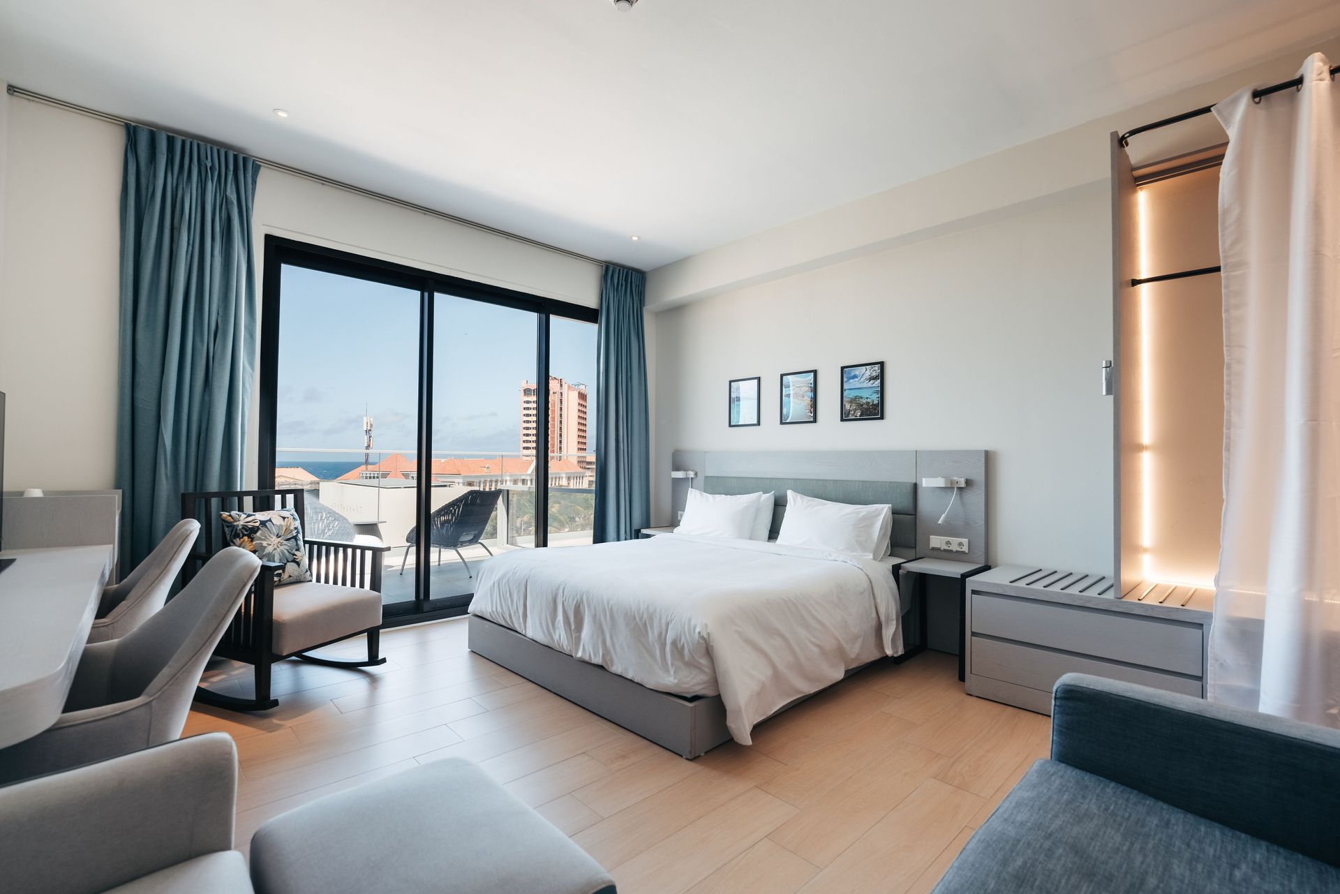 A hotel room with a king size bed , a couch , a desk and a balcony.