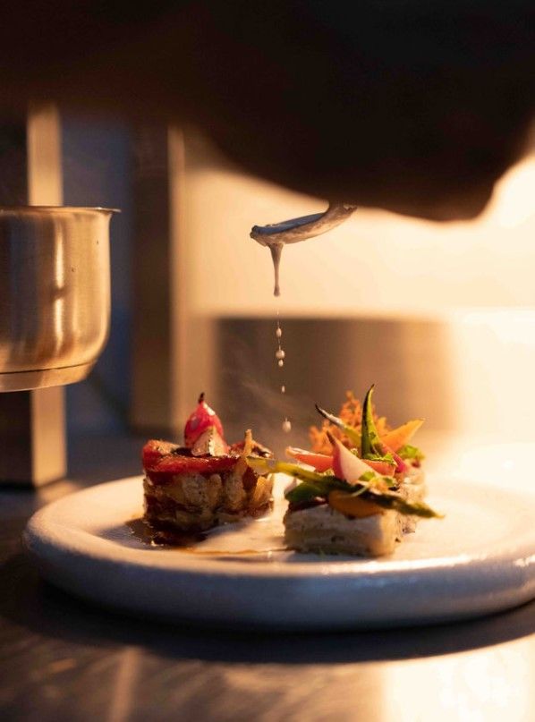 A person is pouring sauce on a plate of food.