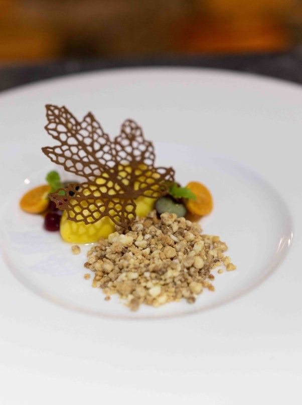 A white plate topped with a chocolate leaf and nuts.