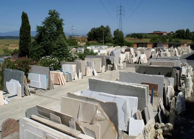 Cortile esterno in pietra con file di lastre di marmo tagliate sotto un cielo azzurro limpido