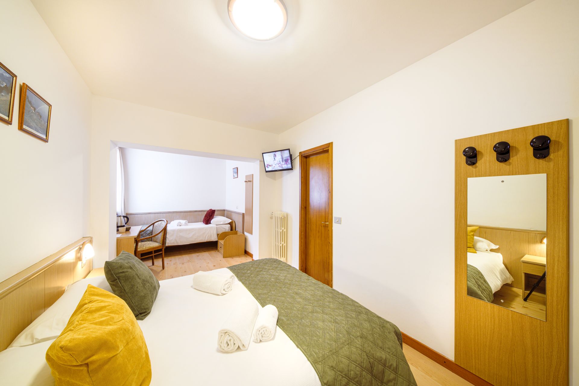 Camera da letto luminosa con letto, pareti bianche, porta in legno e una sedia vicino alla finestra.
