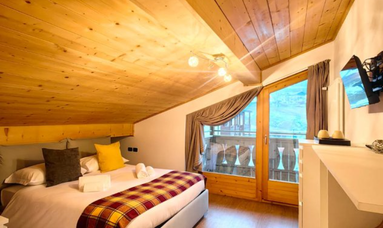 Accogliente camera da letto mansardata con soffitto rivestito in legno