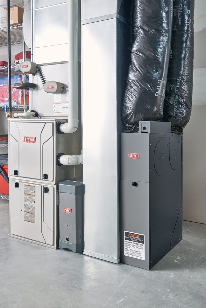 Gray furnace and air handler in a basement, with ductwork.