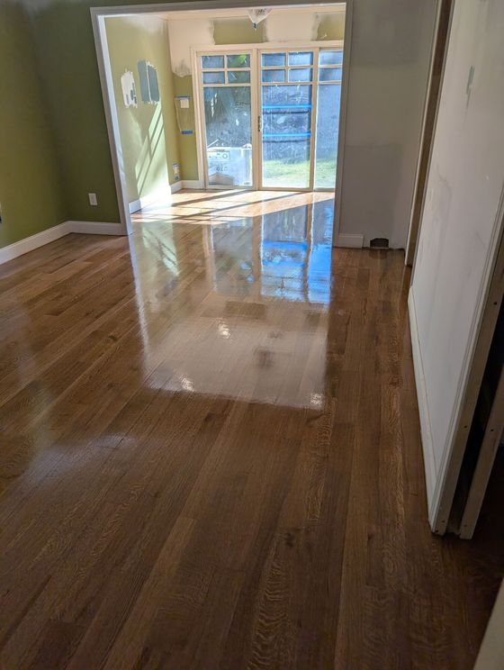 Empty room with hardwood floors and a sliding glass door to a bright balcony.