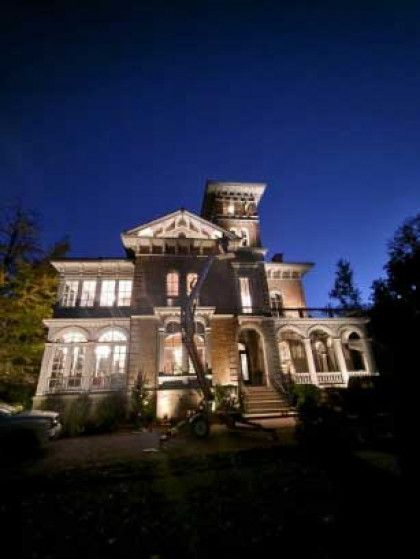Victorian mansion lit at night under a deep blue sky