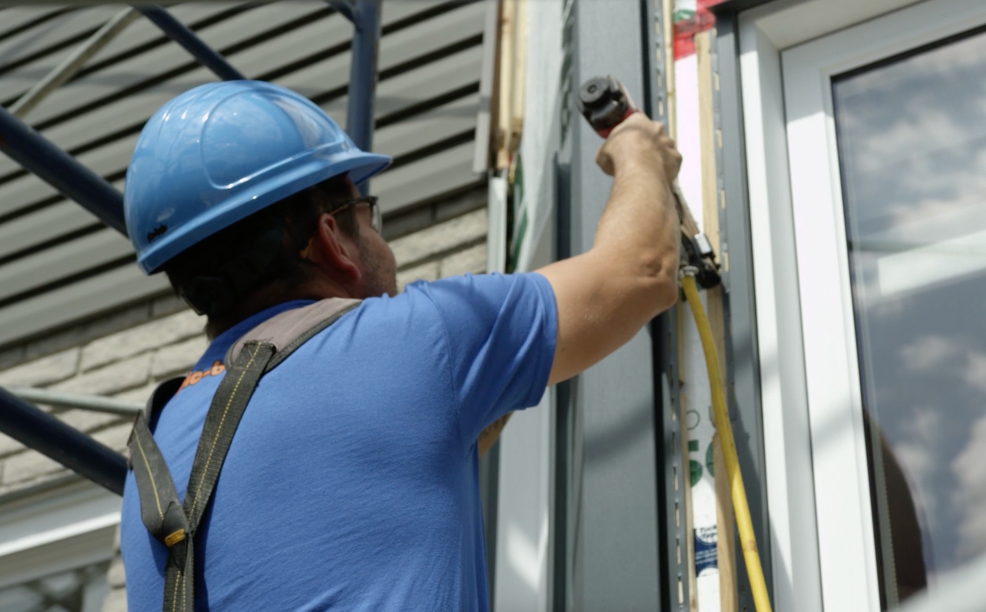 A man wearing a hard hat is working on a window