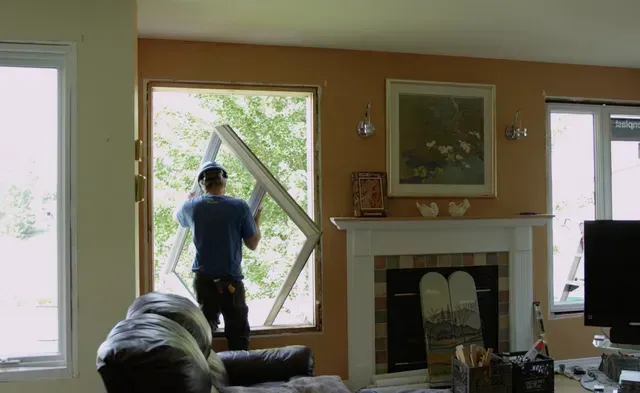 Un ouvrier retire un cadre de fenêtre d'un mur à l'intérieur d'une maison.