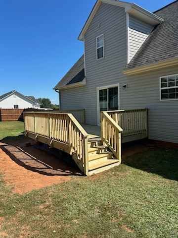 A wooden deck with stairs leading up to it is in front of a house.