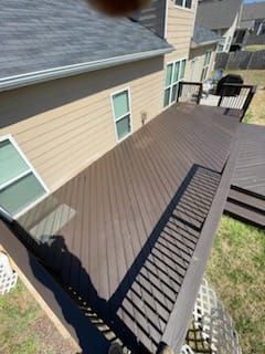 A large wooden deck is sitting in front of a house.