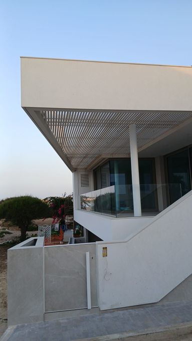 Soggiorno moderno con divano bianco, ampia finestra e porte scorrevoli in vetro che conducono al patio.