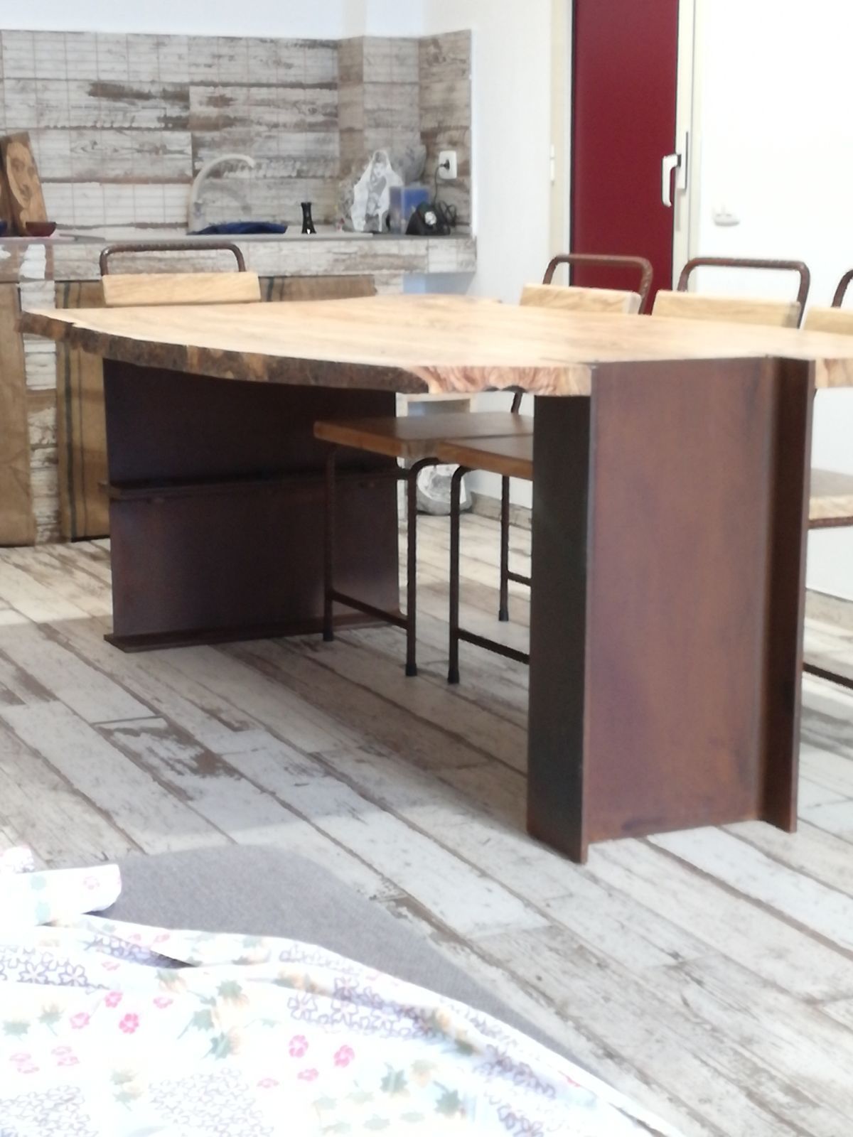Tavolo da pranzo in legno con gambe scure e sedie in una cucina-sala da pranzo in stile rustico.