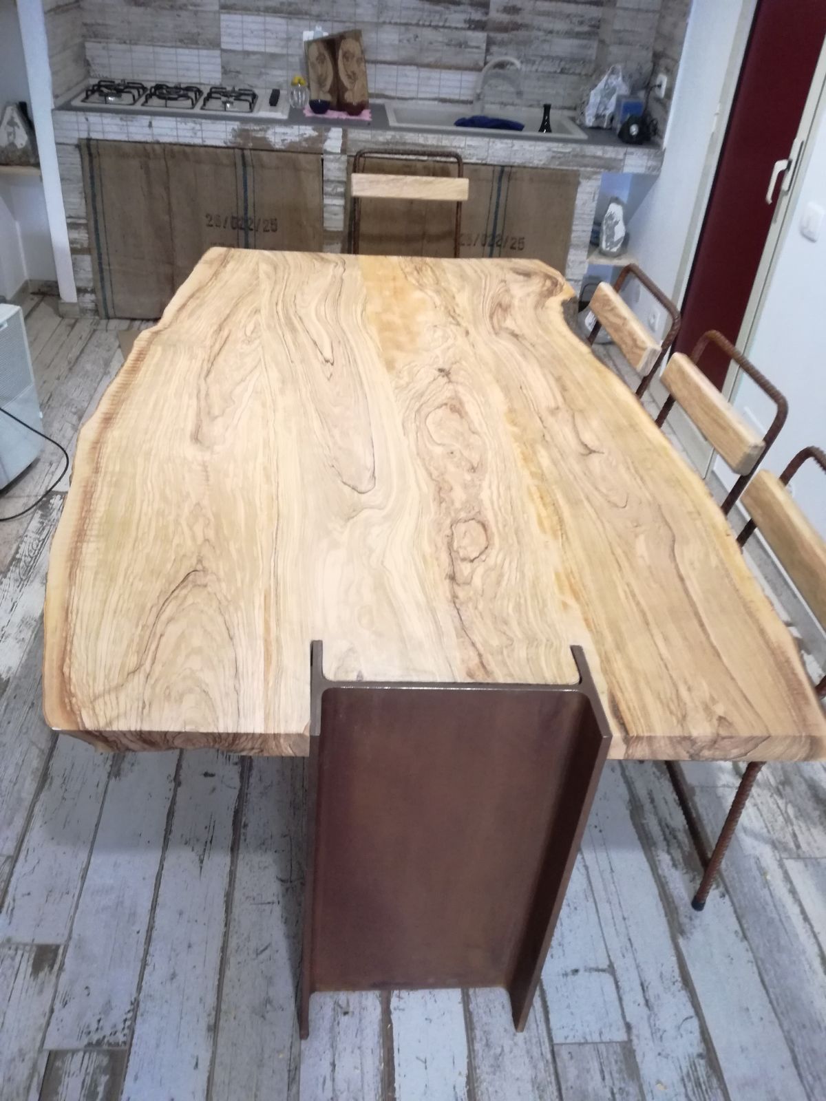 Ampio tavolo da pranzo in legno con sedie, ideale per una cucina o un'officina in stile rustico.